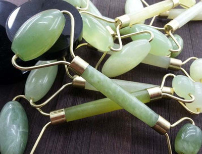 Collection of green Beauty Jade massage facial rollers on wooden surface