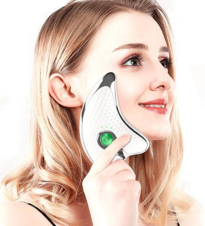 Woman using face neck guasha massager with LED light therapy on cheek